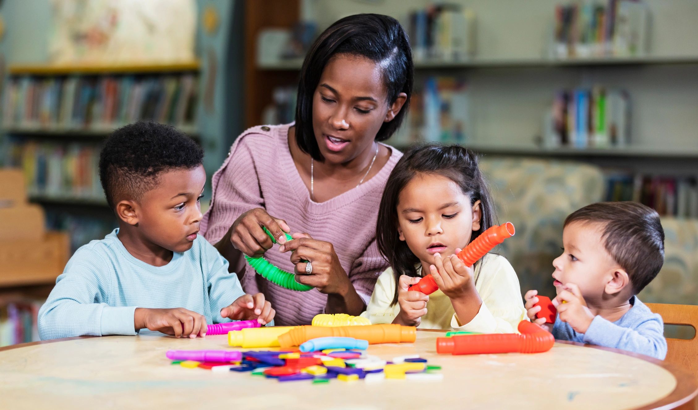 Teacher and preschool children playing with colorful toys