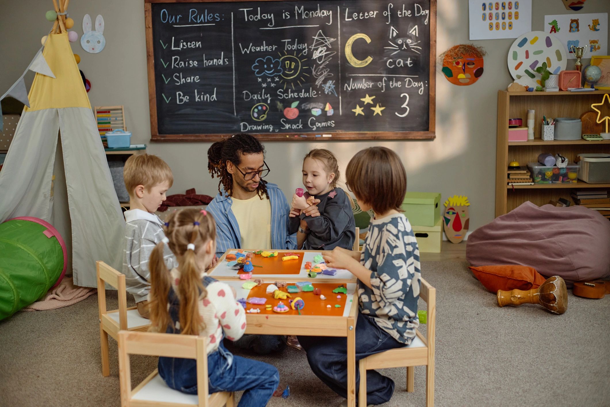 Children creating crafts with a teacher in a kindergarten classroom